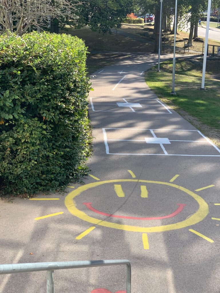 Målad glad sol på skolgårdens asfalt