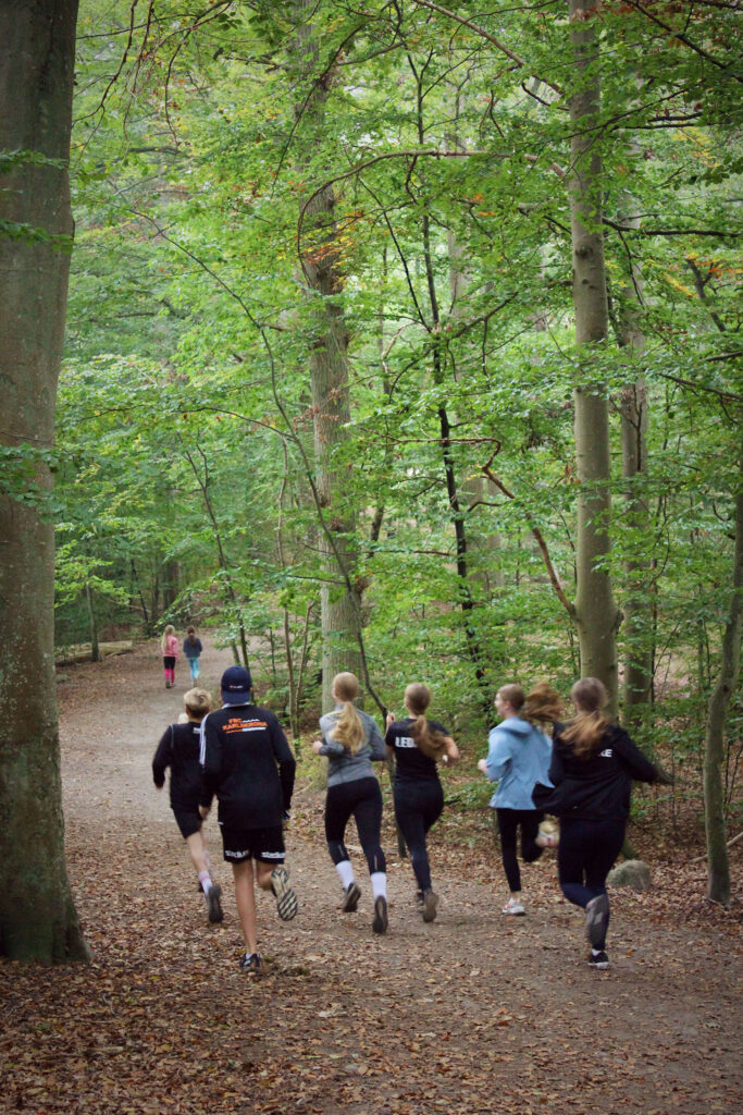 Skolelever joggar runt ett elljusspår under idrottslektion