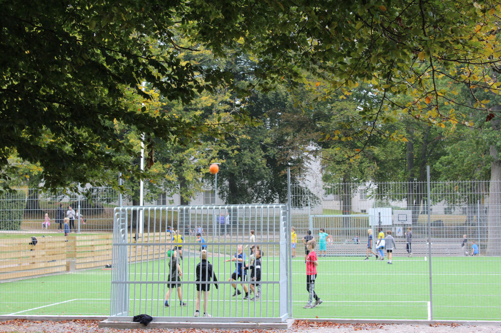 Unga skolelever spelar fotboll på skolans konstgräsplan