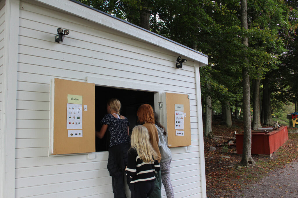 Skolelever hämtar leksaker och aktivitetsmaterial från bod ute på skolgården